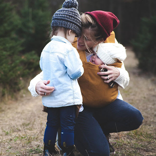 Une maman avec sa petite fille et son bébé dans la forêt