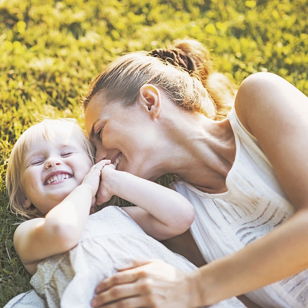 A mother hugs her daughter lying in the grass