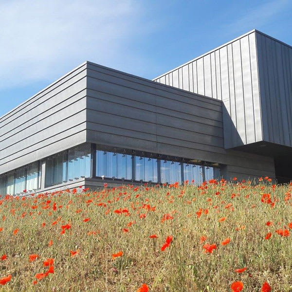 Bâtiment du site d'IRD et de production d'Epernon avec des coquelicots au premier plan