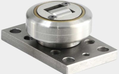 Precision stainless steel cam follower with square internal bore, mounted on a rectangular base plate with multiple mounting holes.