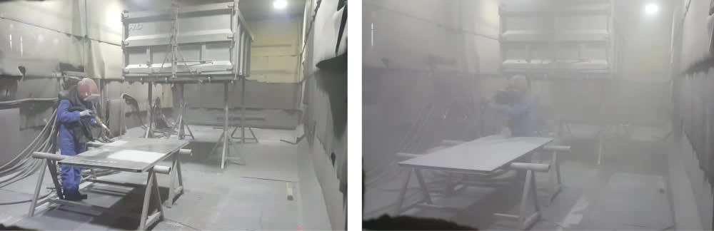 Industrial workers performing abrasive sandblasting on metal parts in a dusty preparation booth, wearing full protective gear.