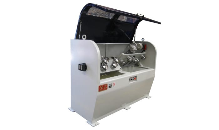 Industrial wire processing machine with an open protective hood revealing multiple guiding rollers, an electric motor, and a liquid basin below