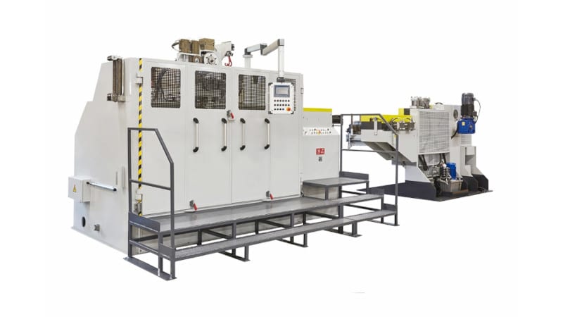 Large white and grey industrial processing machine with a control panel, operator platform, and yellow safety markings.