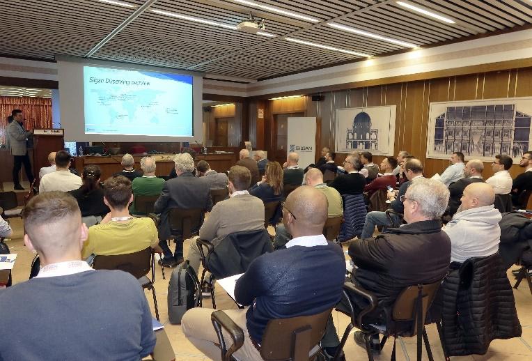 Relatore presenta una panoramica globale di Silgan Dispensing con mappa mondiale su schermo a un pubblico in sala conferenze.