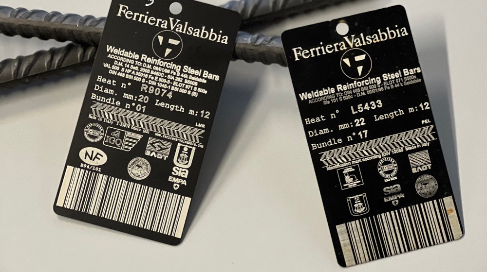 Due etichette nere Ferriera Valsabbia su tondini in acciaio, con dettagli su barre saldabili: diametro 20mm e 22mm, lunghezza 12m, numeri di colata R9074 e L5433, codici a barre e loghi di certificazione.