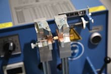 Stumpfschweißmaschine im Detail, die zwei Kupferdrähte präzise miteinander verbindet.