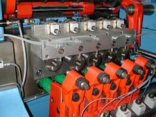 Macchinario industriale automatizzato con un sistema di moduli meccanici e una serie di unità operative rosse.