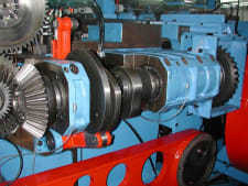 Máquina industrial azul y negra para mecanizado de un diferencial y engranajes grandes, incluyendo engranajes cónicos.