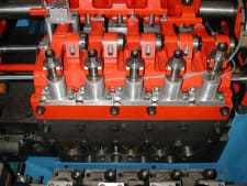 Macchinario industriale rosso con una fila di unità di processo metalliche lucide.