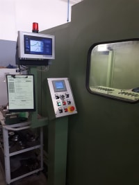 Macchinario industriale verde con pannello di controllo HMI, monitor di supervisione dati e finestra di ispezione interna.