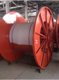 Large red industrial steel cable reels, one with a prominent gray core, in a warehouse.