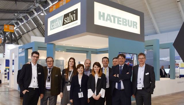 Team di professionisti Carlo Salvi e Hatebur sorridenti davanti al loro stand espositivo in fiera.