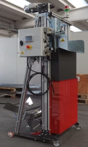 Automatisierte Industriemaschine mit Bedienfeld, Not-Aus-Taste, dreifarbiger Signalsäule und fahrbarem Unterbau mit roter Verkleidung in einer Produktionshalle.