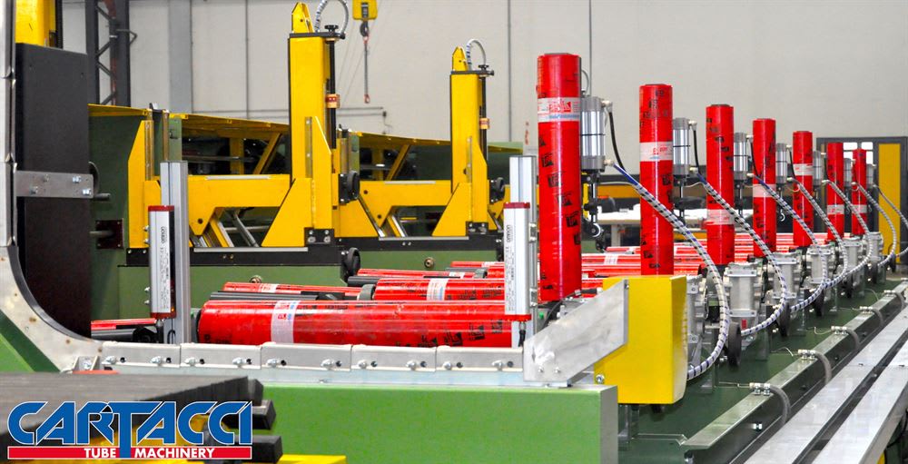 Cartacci tube machinery processing red cylindrical products on an automated production line with yellow support structures.