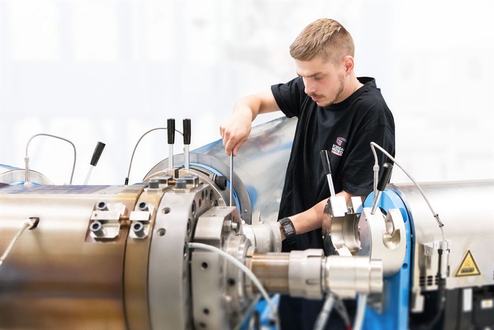 ROBODRILL NITEO technician adjusting components on a large industrial processing machine with a hand tool.