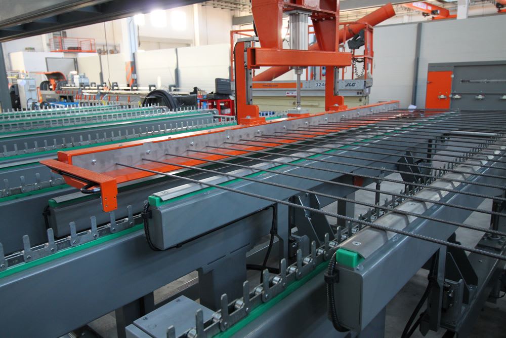 Automated industrial rebar welding machine processing multiple steel reinforcement bars on a conveyor system.