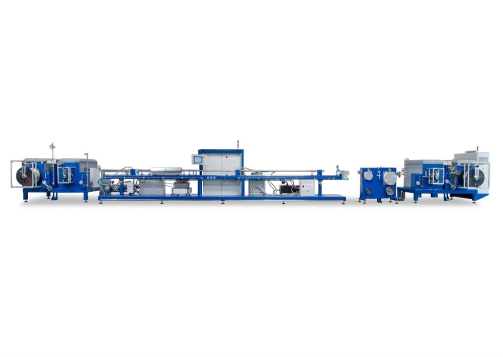 Long blue and white industrial extrusion line for continuous material processing, featuring an unwinding unit, multiple modular processing stations, and a central control panel.