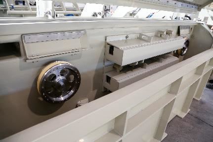 Industrial machine detail showing a large metal gear and light-colored modular processing components.