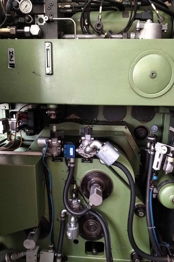 Green industrial machinery with visible hydraulic pipes, pneumatic valves, pressure gauges, and a liquid level indicator.