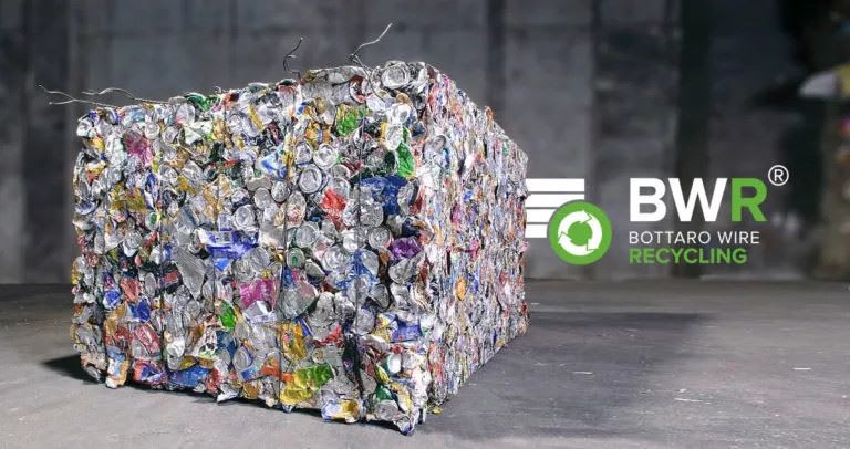 Balle compactée de canettes en aluminium recyclées multicolores, liée par des fils, avec le logo vert de Bottaro Wire Recycling en arrière-plan.