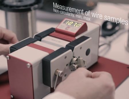 Mesure de non-circularité d'échantillons de fil : une personne utilise un appareil de précision affichant '10.70' pour le contrôle qualité.
