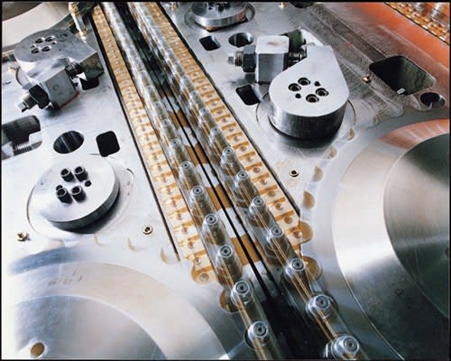 Stampo industriale in metallo lucidato con elementi di fissaggio, canali paralleli e componenti meccanici di precisione.