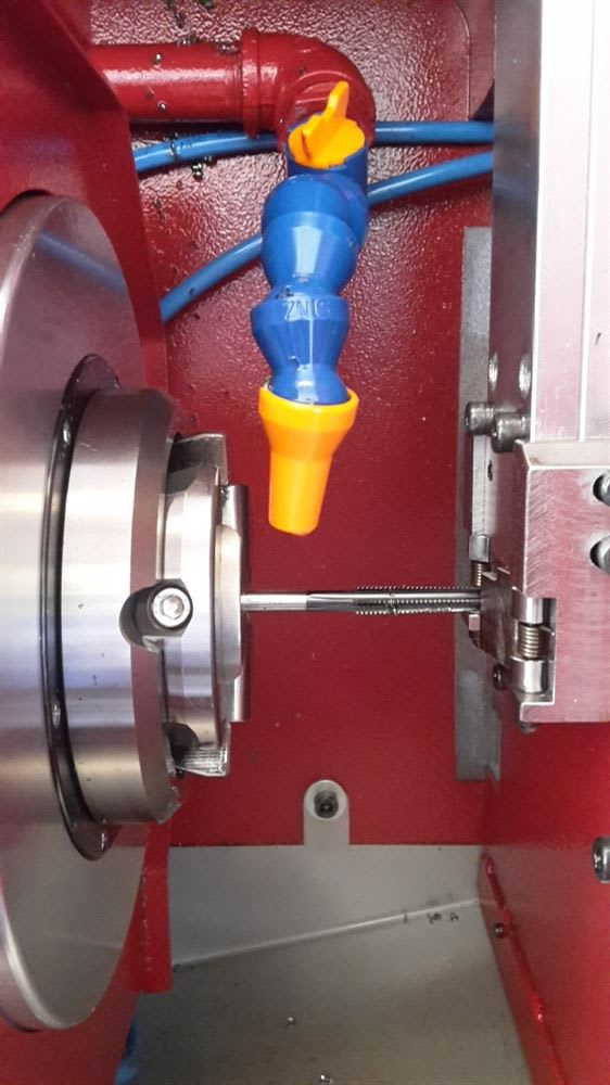 Lavorazione di maschiatura su macchina utensile con utensile nel mandrino, ugello del refrigerante e trucioli metallici.