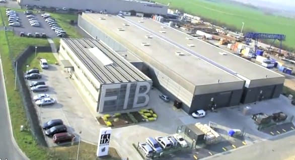 Aerial view of the FIB industrial complex featuring modern buildings, employee parking lots, and surrounding green landscape.