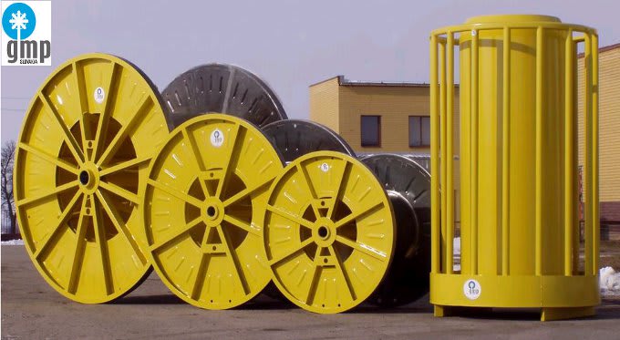 Bobine e tamburi industriali in metallo giallo di varie dimensioni per cavi, a marchio GMP Suwałki, con una struttura cilindrica verticale.