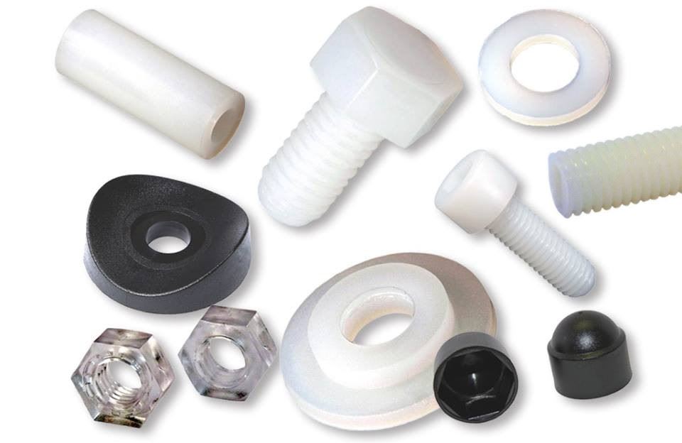 Assortimento di elementi di fissaggio in plastica, inclusi viti a testa esagonale, viti a testa cilindrica, dadi esagonali, rondelle piane e coniche, distanziali e tappi copridado, in colori bianco traslucido, trasparente e nero.
