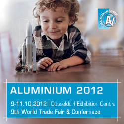 Young boy with curly hair lying on the floor, intently observing three silver rocket models. Promotes ALUMINIUM 2012, the 9th World Trade Fair & Conference in Düsseldorf, 9-11 October 2012.