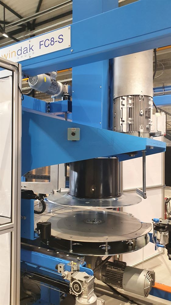 Blue Windak FC8-S industrial coiling machine with a visible electric motor, a black cylindrical spool, and large metallic rotating discs.