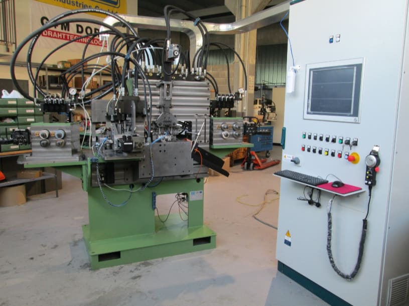 Macchina industriale automatizzata per la lavorazione di fili metallici con sistema idraulico e pannello di controllo digitale, situata in un'officina.