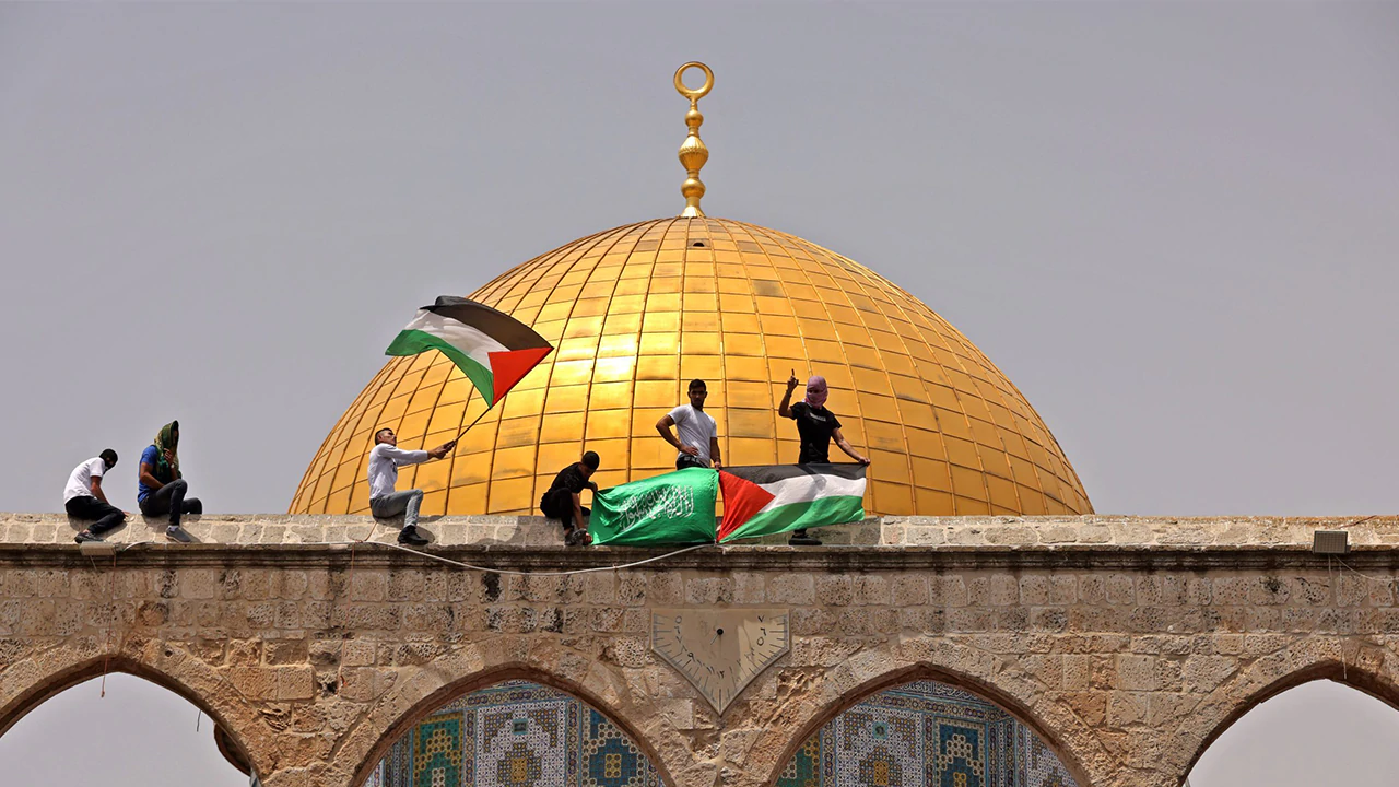 Palestinian Muslim worshippers wave the Palestinian and Hamas flags during clashes with Israeli security forces in Jerusalem's Al-Aqsa Mosque compound on May 21, 2021