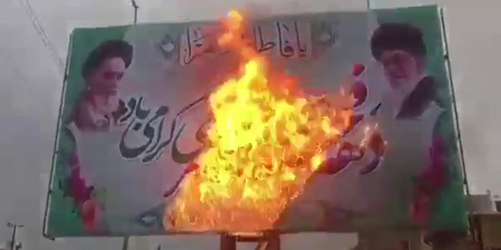 A poster of Ayatollah Ruhollah Khomeini and Ebrahim Raisi is burned