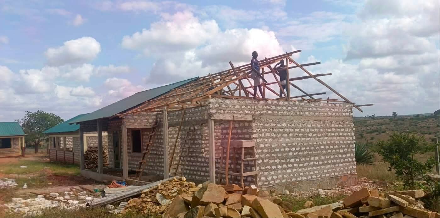 Construction site showing new school building with workers laying bricks and scaffolding in place
