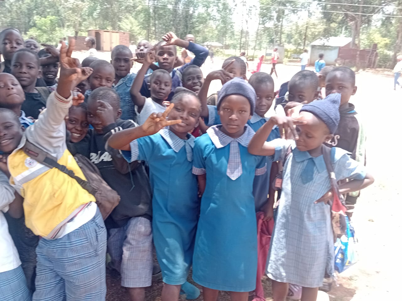 Excited young African children in school uniforms holding up their new school bags and supplies on enrollment day