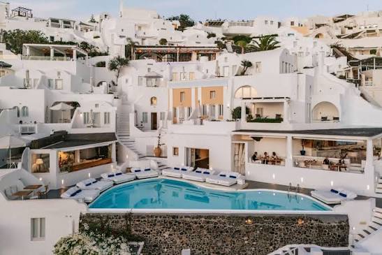 Whitewashed buildings and infinity pools on the Oia caldera cliff at Katikies Santorini
