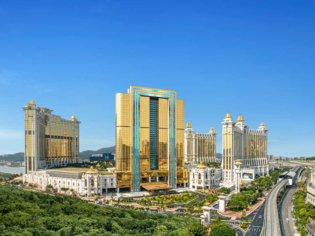 Golden-hued all-suite tower of Raffles at Galaxy Macau rising above the Cotai Strip