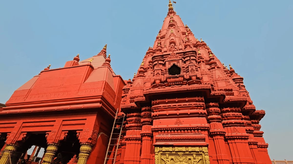 Multitiered red sandstone spire of Durga Temple beside the ancient stone Durga Kund tank