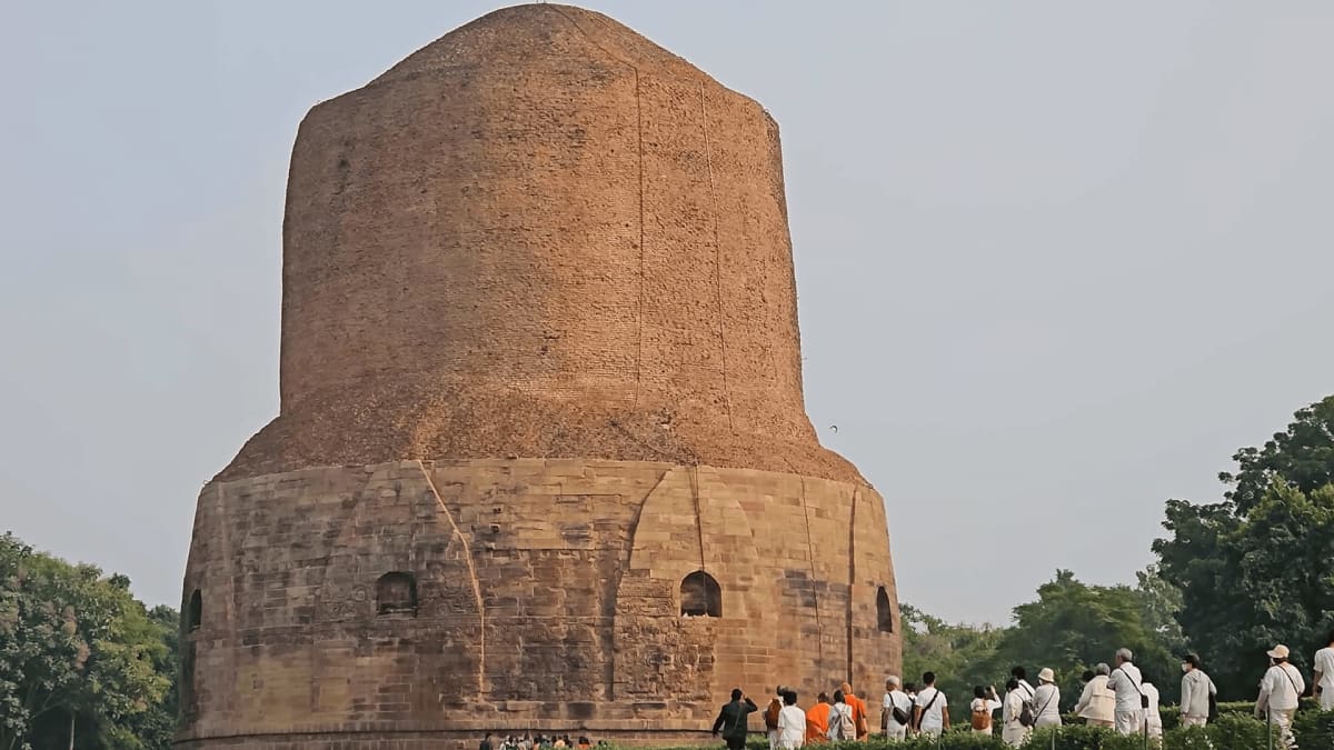 Monolithic cylinder shaped ancient stone Dhamek Stupa at Sarnath surrounded by green gardens