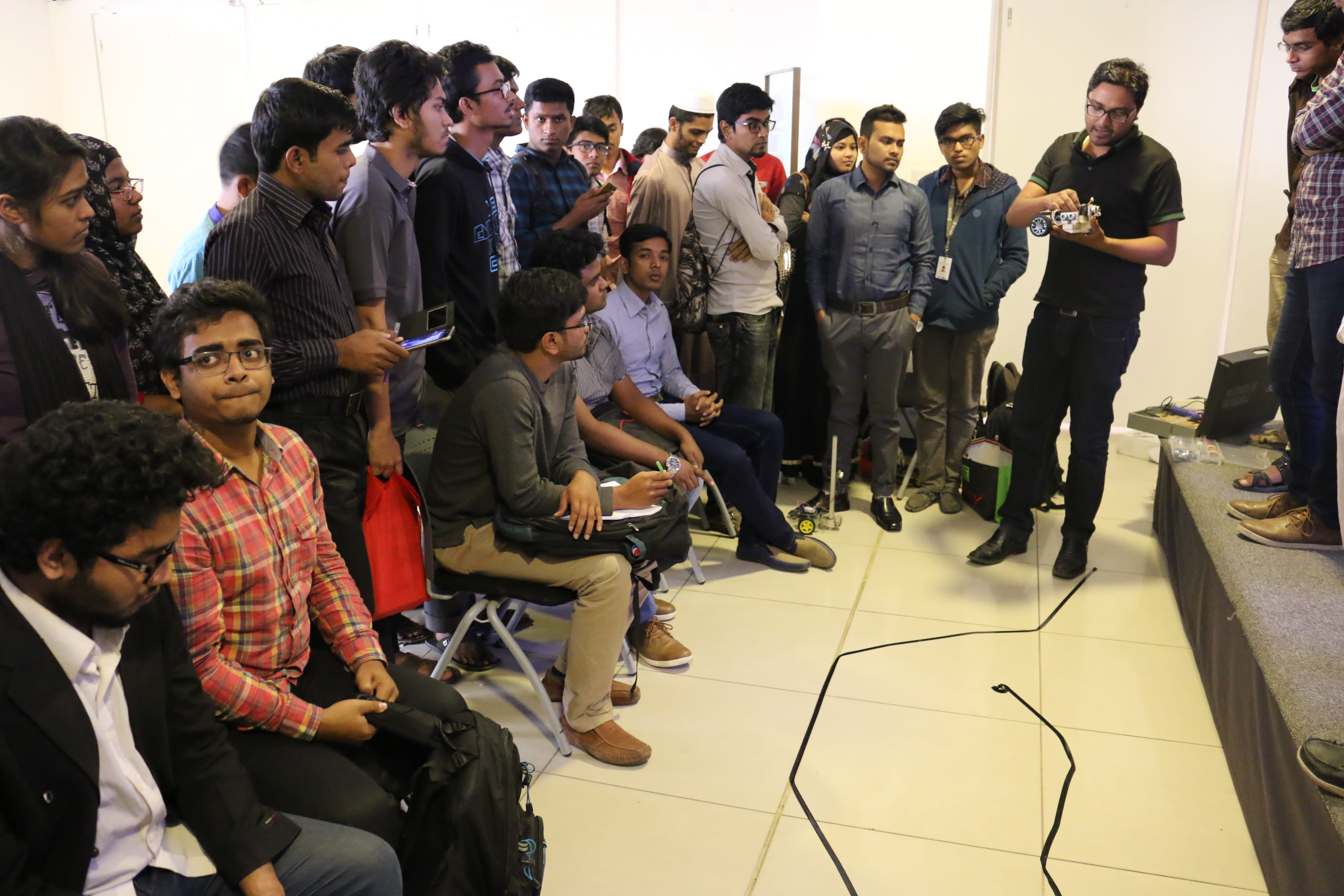 Demonstrating a working line follower robot to participants beside the test track