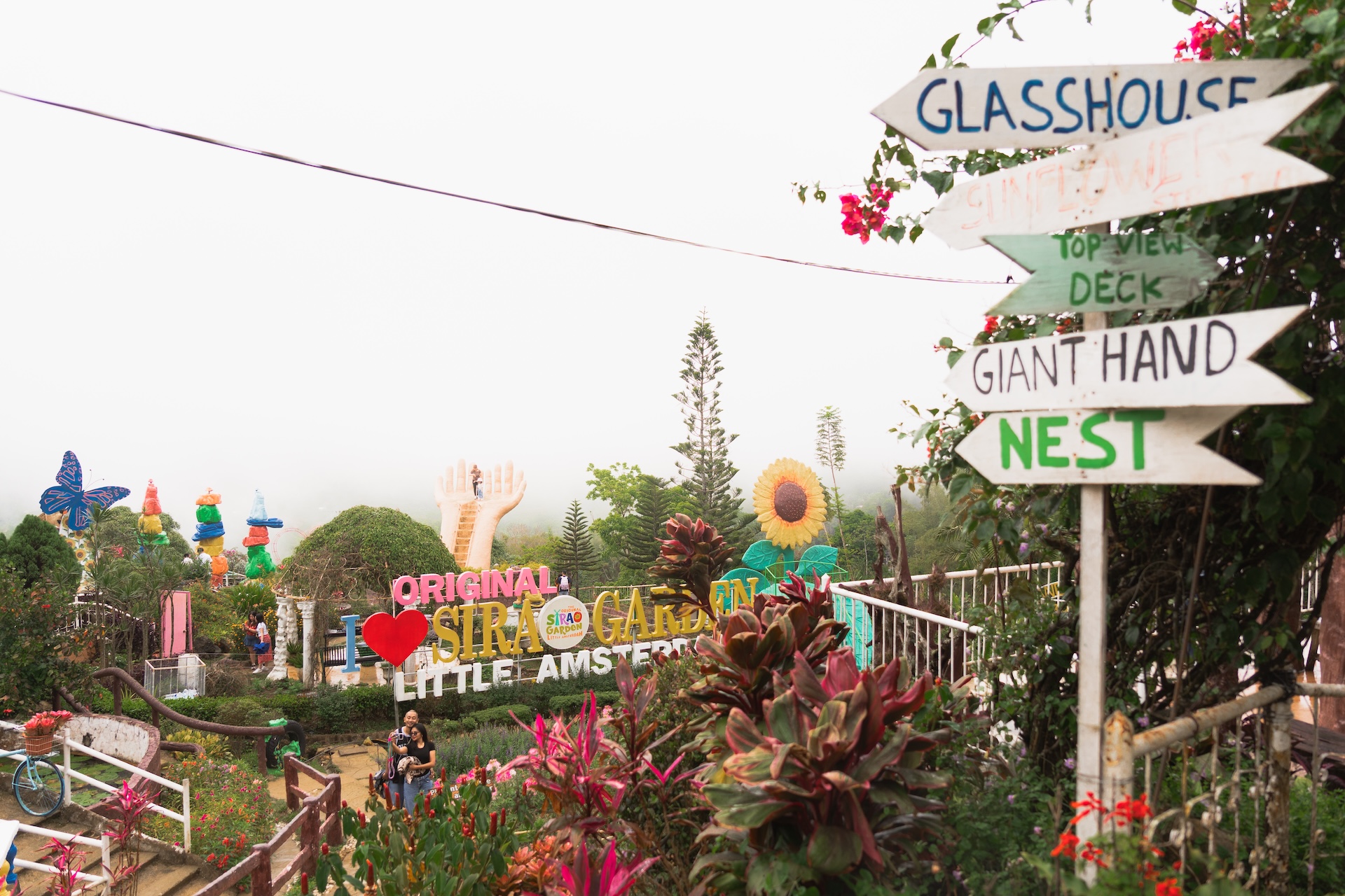 Panoramic view of Sirao Garden Cebu with directional signpost pointing to Glasshouse Giant Hand and Nest