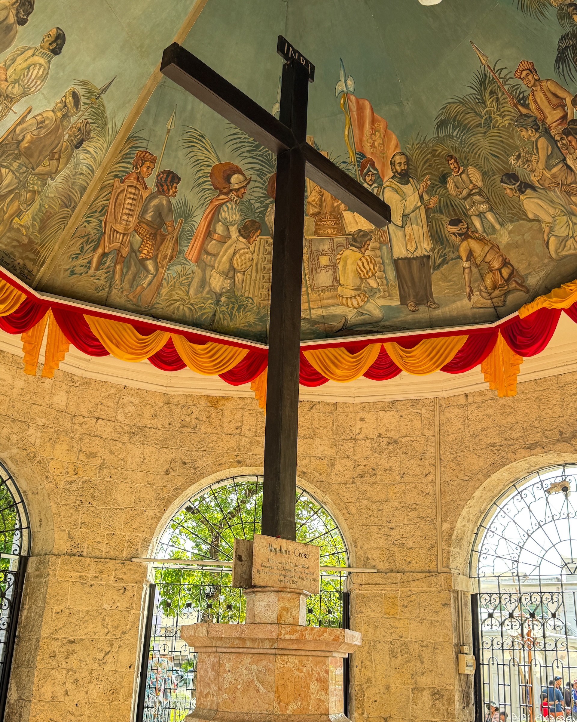 Magellan&rsquo;s Cross encased in tindalo wood inside the pavilion with historic baptism mural on the ceiling