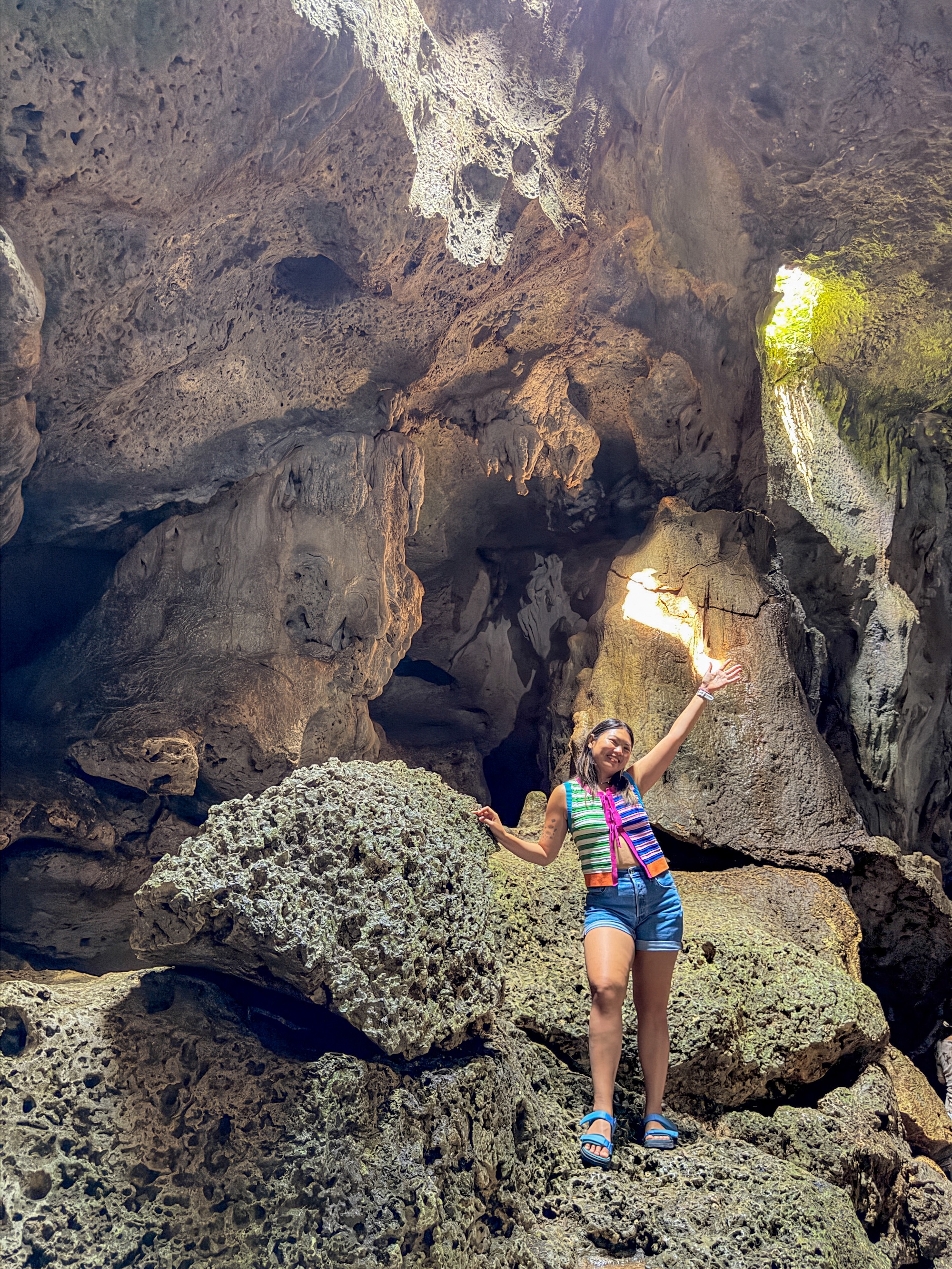 Woman posing inside Hinagdanan Cave with sunlight streaming through the rock opening in Panglao, Bohol