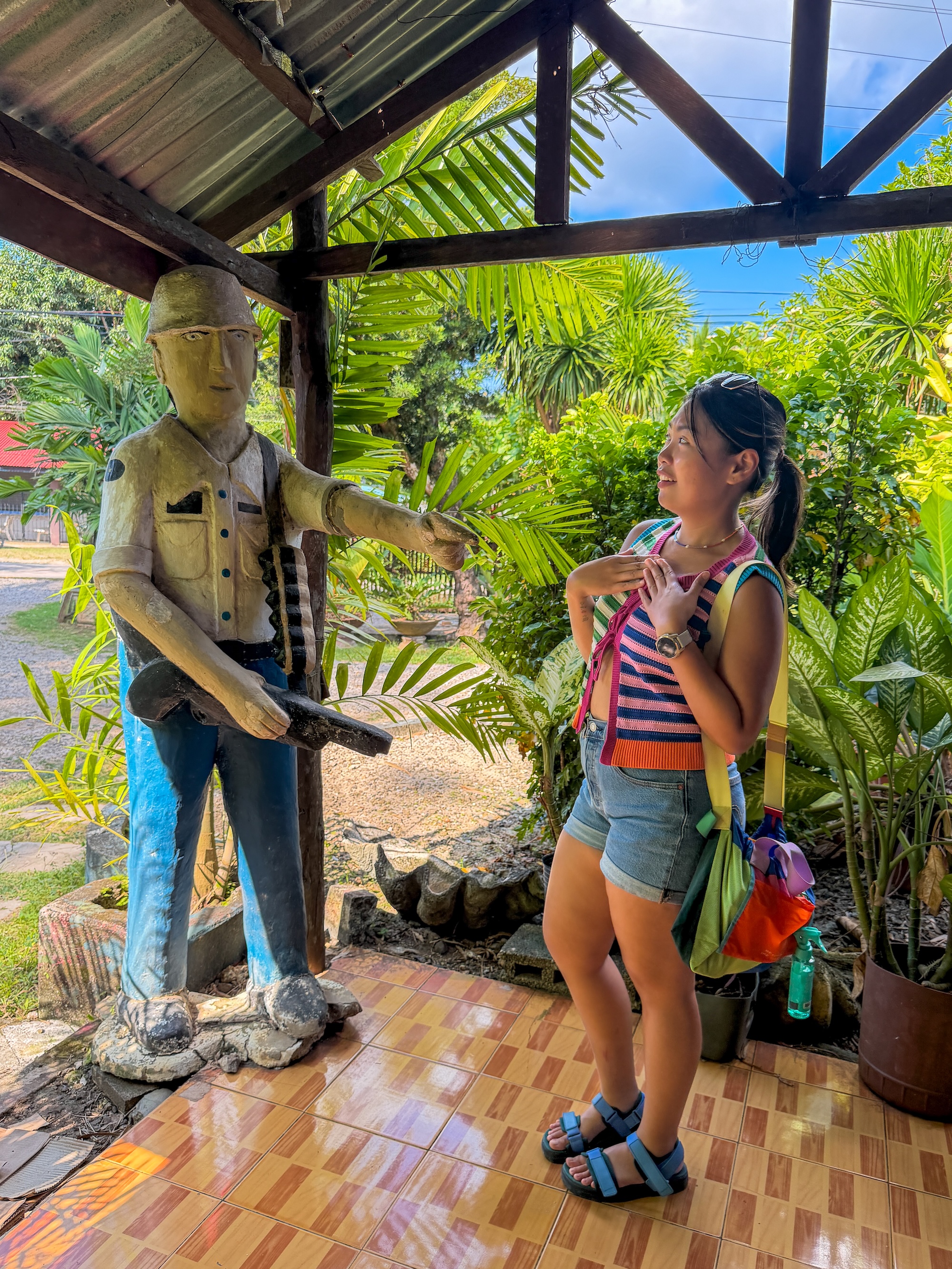 Woman posing beside a life-sized guerrilla soldier statue at Bohol Bee Farm