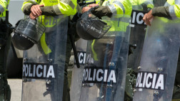 image shows police in riot gear with shields reading 'policia'