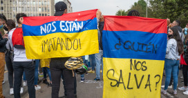 two people at a protest are holding Colombian flags