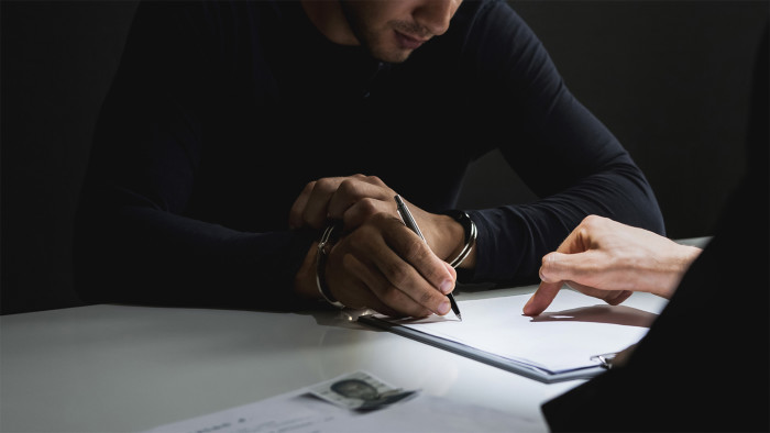 Man in handcuffs signing a document