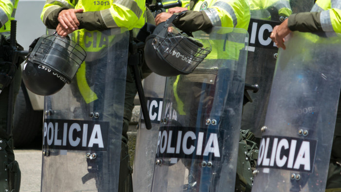 image shows police in riot gear with shields reading 'policia'